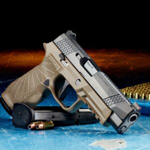 a handgun resting on a ammunition clip and 2 rounds of bullets. in the background a tray of rounds.