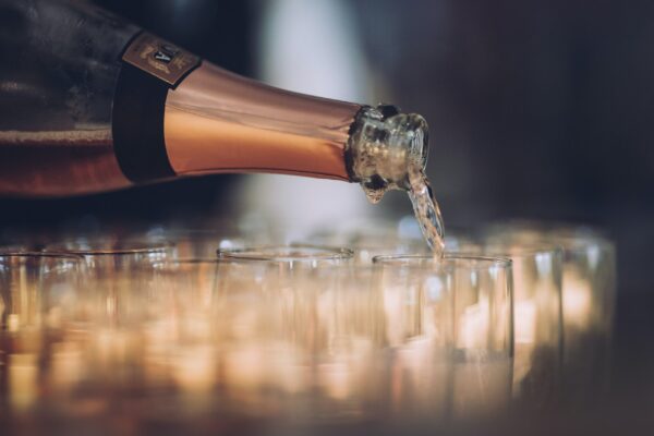 Prosecco pouring from a gold topped bottle into champagne glasses.